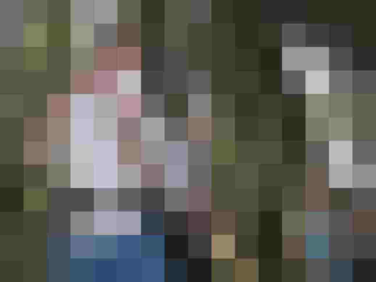 Eine Gruppe von Personen im Wald, einer hält eine Kamera und lächelt.
