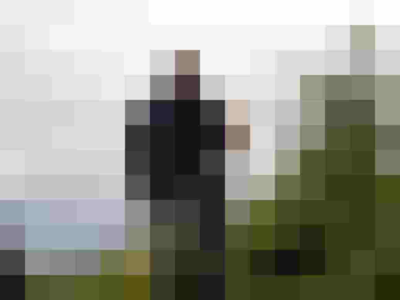 Mann mit Bogen auf einem Bogenparcours in der Natur, Landschaft im Hintergrund.